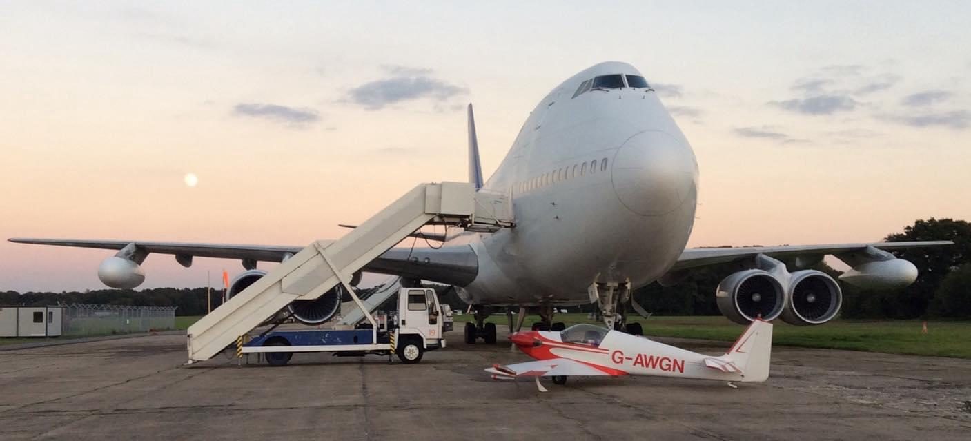 G-AWGN parked in front of a Boeing 747 at dusk