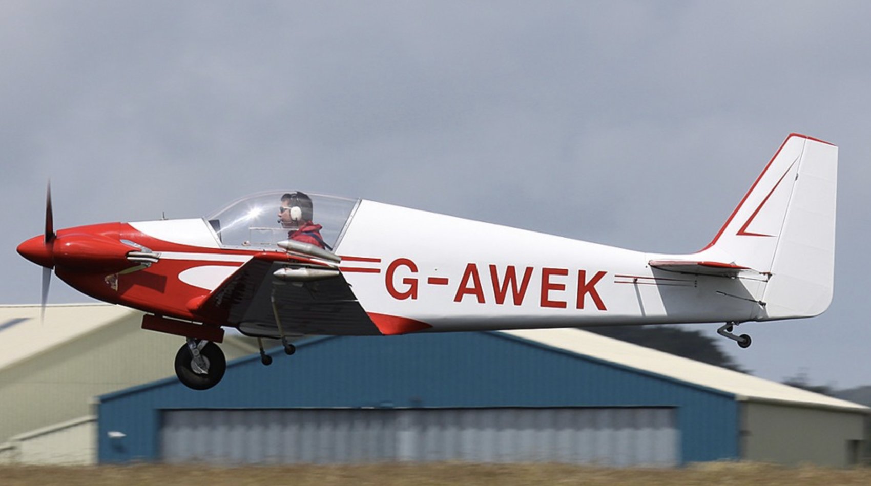 G-AWEK taking off, hangar behind