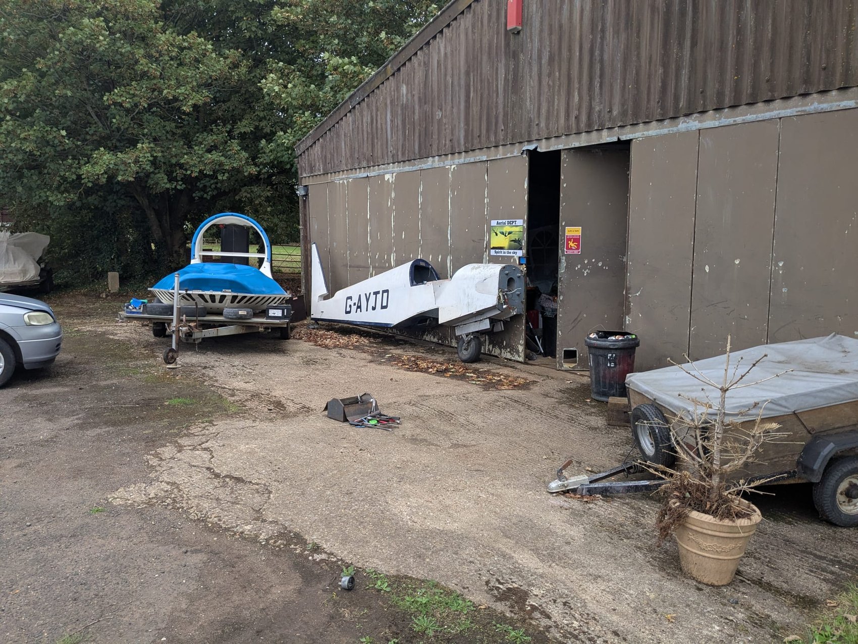 G-AYJD’s fuselage outside a barn marked “Aerial Dept — Spirit in the Sky”