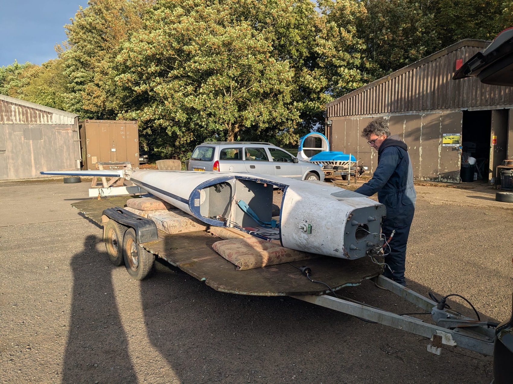G-AYJD wing and fuselage section loaded on a trailer, being worked on