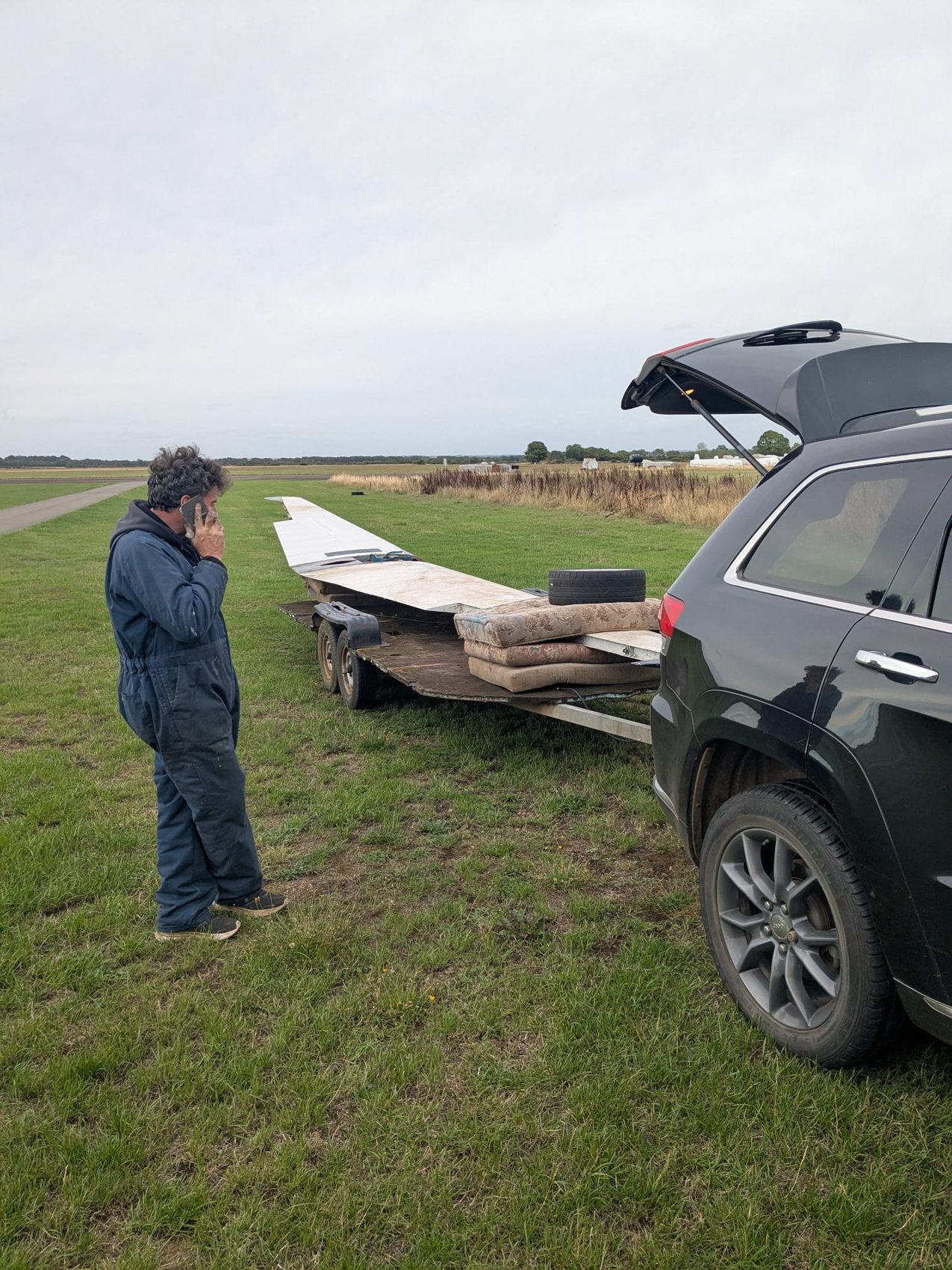 Loaded trailer with G-AYJD’s wing, parked on the grass at an airfield